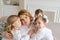 We love you. Smiling young woman, kids hug mom while sitting on sofa in living