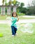 Lovely active little asian girl playing with soap bubble outdoor in the park