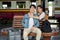 A lovely Asian female embraces her beloved boyfriend while resting on a bench at the railway station