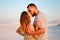 Lovely attractive couple kissing on the white sand beach or in the desert or in the sand dunes, happy couple embracing at the beac