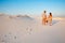 lovely attractive couple on the white sand beach or in the desert or in the sand dunes, guy and a girl with a basket in their han