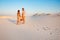 Lovely attractive couple on the white sand beach or in the desert or in the sand dunes, guy and a girl with a basket in their hand