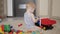 Lovely baby boy playing with a big car toy on floor at home. Kid boy toddler playing with toy car indoors. Future driver