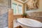 Lovely bathroom boasts jetted tub with a brown mosaic tile surround