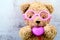 lovely bear doll wearing pink glasses and holding pink heart shape