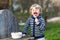 Lovely blond boy of two years eating strawberries outdoors