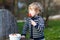 Lovely blond boy of two years eating strawberries outdoors