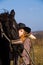 Lovely blond woman in a hat standing by horse