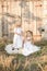 Lovely blonde girl sisters in white dresses and straw hats laugh and eat apples in the countryside