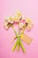 Lovely bouquet of daffodils with blank label card on pink background, top view.