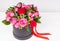 Lovely bouquet of pink and red roses and red ribbon in a circular black box on white wooden table