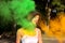 Lovely brunette woman with short hair posing with exploding green and orange Holi paint