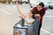 Lovely cheerful vietnamese girl scattering money ,sitting in the shopping trolley which holding her attractive boyfriend