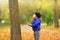 Lovely child catches the maple leaves in the fall during autumn