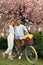 Lovely couple with bicycle and flowers in park on pleasant spring day