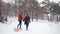 Lovely couple walking pulling sled on snowy winter day. Man with girlfriend go sledding on snowfall. Woman going to