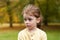 Lovely cute red-haired little girl in the autumn park outdoors. Lovely baby in front of falling leaves