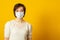 Lovely dark haired lady has epidemic disease, wears protective medical mask,  has infection, stands indoor. Health care and people