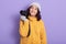 Lovely dark haired woman taking photo with camera isolated over lilac background, adorable female dresses yellow knitted sweater,