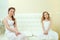 Lovely elegant sisters sitting on white couch