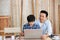 Lovely father and son are helping to design a wooden house with a laptop