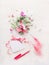 Lovely flowers bunch and blank greeting card with pink ribbon and pen or marker on white wooden background.