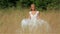 Lovely gentle blonde bride dancing in a wheat field in white bridal dress