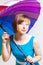 Lovely girl in blue dress holding colorful positive rainbow Umbrella on white background. Studio shot, copy space