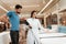 Lovely girl consultant demonstrates orthopedic mattress to confident man in furniture store.