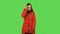 Lovely girl in a red down jacket is coquettishly smiling while looking at camera . Green screen