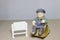 Lovely grandparent doll siting rocking bamboo chair on wood background. -still life.