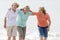 Lovely group of three senior mature retired women on their 60s having fun enjoying together happy walking on the beach smiling pla