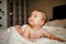 Lovely Happy Baby With Surprised Blue Eyes Close-up. Infant Playing Home On Bed In Morning.