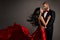 Lovely Happy Couple dancing. Woman in red Dress and Man in Black Suit with Bow Tie. Flying silk Fabric and hair on Wind. Studio