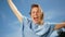 Lovely happy girl in a denim dress. Sunny portrait of a young woman with a white-toothed smile against the sky