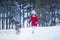 Lovely joyful girl running with a dog in the winter forest