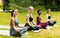 Lovely ladies in sportswear engaged in yoga meditation at beautiful green park, copy space