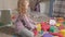 Lovely laughing little kid, preschool blonde, playing with colorful toys, sitting on the floor in the room