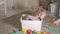 Lovely laughing little kid, preschool blonde, playing with colorful toys in a white box, sitting on the floor in the