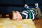 Lovely little boy in striped jumper laying on the floor in the house.