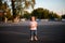 Lovely little girl with blond hair stands alone on the road