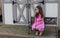 Lovely little girl at chair in the deck park with pink dress during summer in Michigan