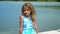 The lovely little girl poses for photos on the boat on water at a pier
