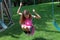 Lovely little girl at swings in the park with pink dress during summer in Michigan