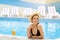 Lovely millennial woman relaxing at poolside with cool summer cocktail, empty space