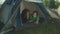 Lovely multiracial women hikers lying in camping tent, checking photos on phone on mountain hiking