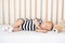 Lovely newborn baby in bodysuit napping in comfortable crib