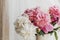 Lovely peony bouquet in sunny light on rustic wooden window sill. Stylish pink and white peonies in vase. Hello spring. Happy