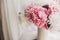 Lovely peony bouquet in sunny light on rustic wooden window sill. Stylish pink and white peonies in vase on wooden background.