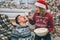 Lovely picture of young woman stands and feeding her boyfriend. She holds piece of popcorn above his mouth. Guy keeps